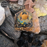 Orgonite Pyramidale de 6 cm de Côté en Résine avec des Pépites en Obsidienne Noire et 1 Boule en Œil de Tigre, du Métal et un Décor Arbre de Vie sur tourmaline