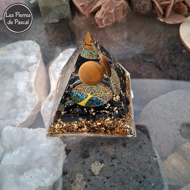 Orgonite Pyramidale de 6 cm de Côté en Résine avec des Pépites en Obsidienne Noire et 1 Boule en Œil de Tigre, du Métal et un Décor Arbre de Vie sur pierre de lave