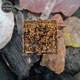 Orgonite Pyramidale de 6 cm de Côté en Résine avec des Pépites en Obsidienne Noire et 1 Boule en Œil de Tigre, du Métal et un Décor Arbre de Vie vue du dessous