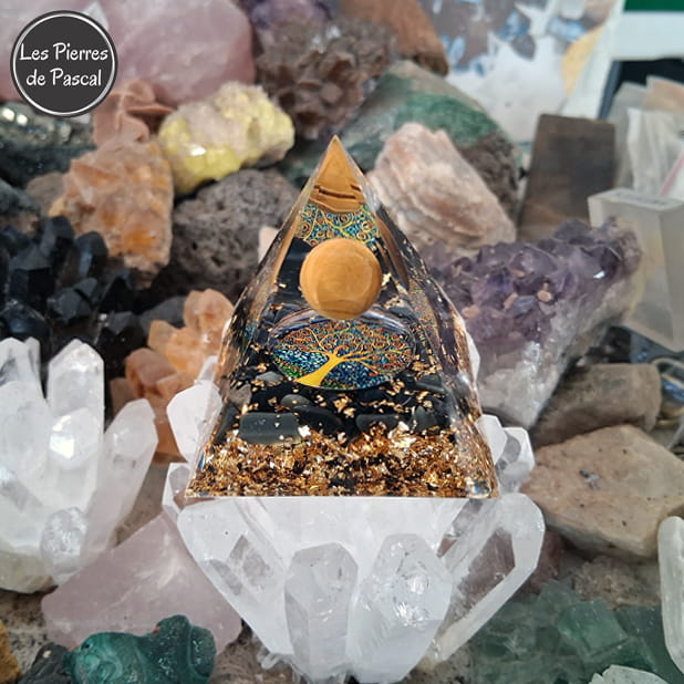Orgonite Pyramidale de 6 cm de Côté en Résine avec des Pépites en Obsidienne Noire et 1 Boule en Œil de Tigre, du Métal et un Décor Arbre de Vie sur 1 druse en cristal