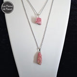 Pendentifs Rhodochrosite Brute d'Argentine 2A avec une Chaîne en Métal Argenté de 50 cm sur un buste blanc