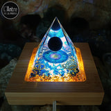 Orgonite Pyramidale de 6 cm Lumineuse en Résine "Protection et Anti-Ondes" avec une Boule de Tourmaline Noire sur un Socle en Bois Éclairant
